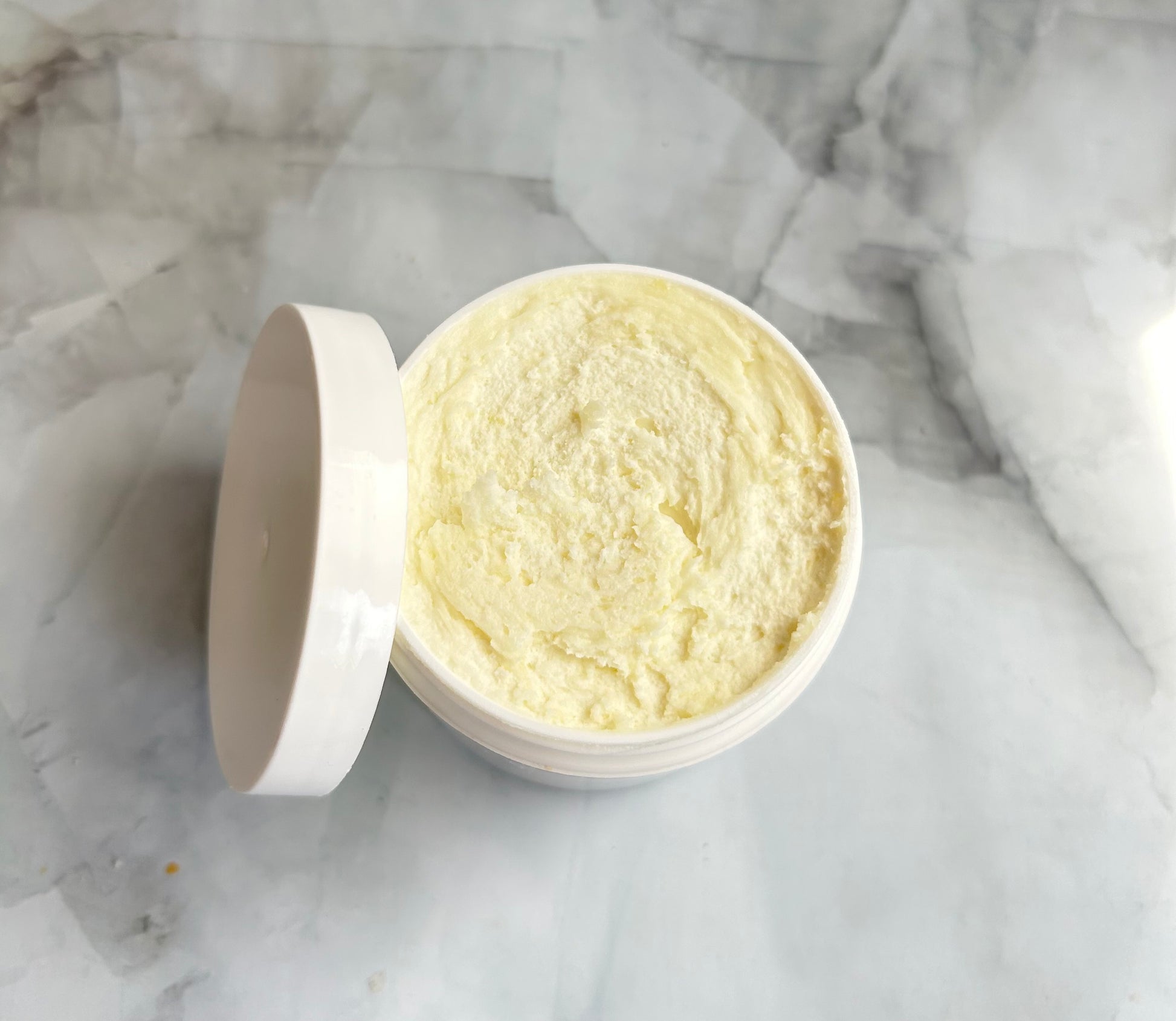 Open container of cream on a marble surface
