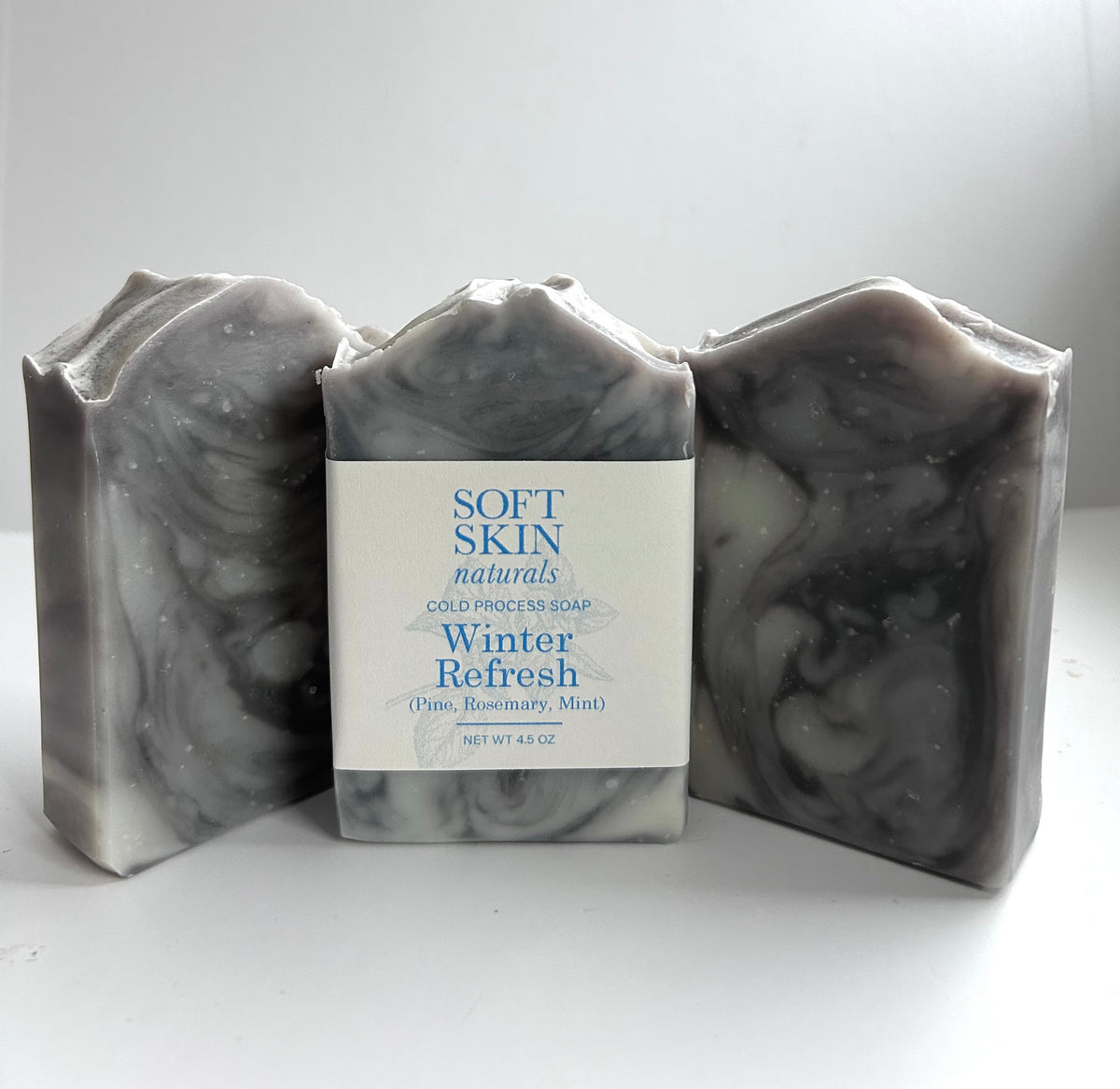 Three bars of marbled soap with a 'Soft Skin Naturals' label on a white background