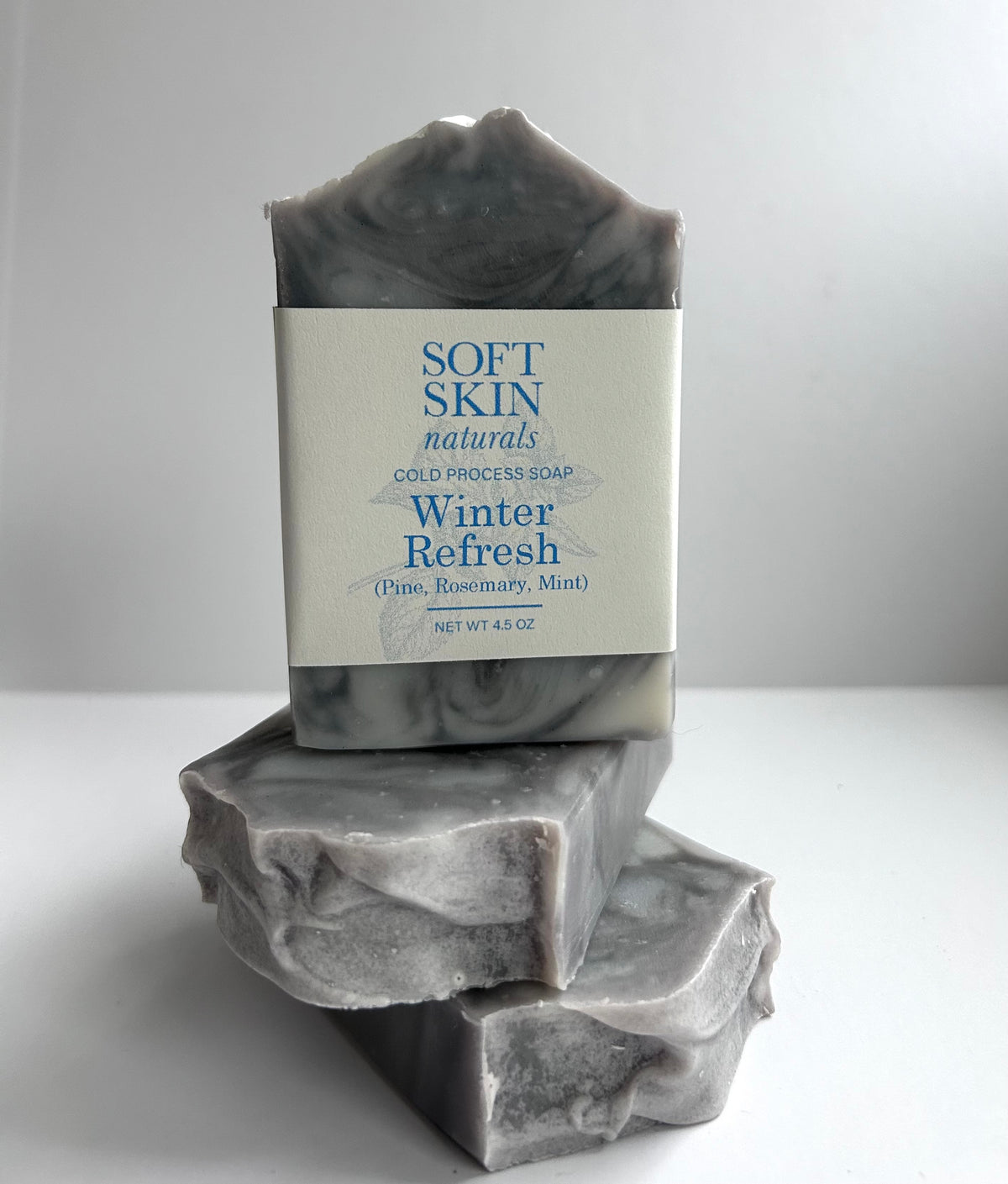 Three bars of 'Soft Skin Naturals' soap with a label on a white background
