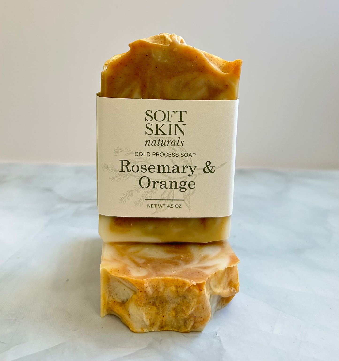 Two bars of soap with a 'Soft Skin Naturals' label on a marble surface