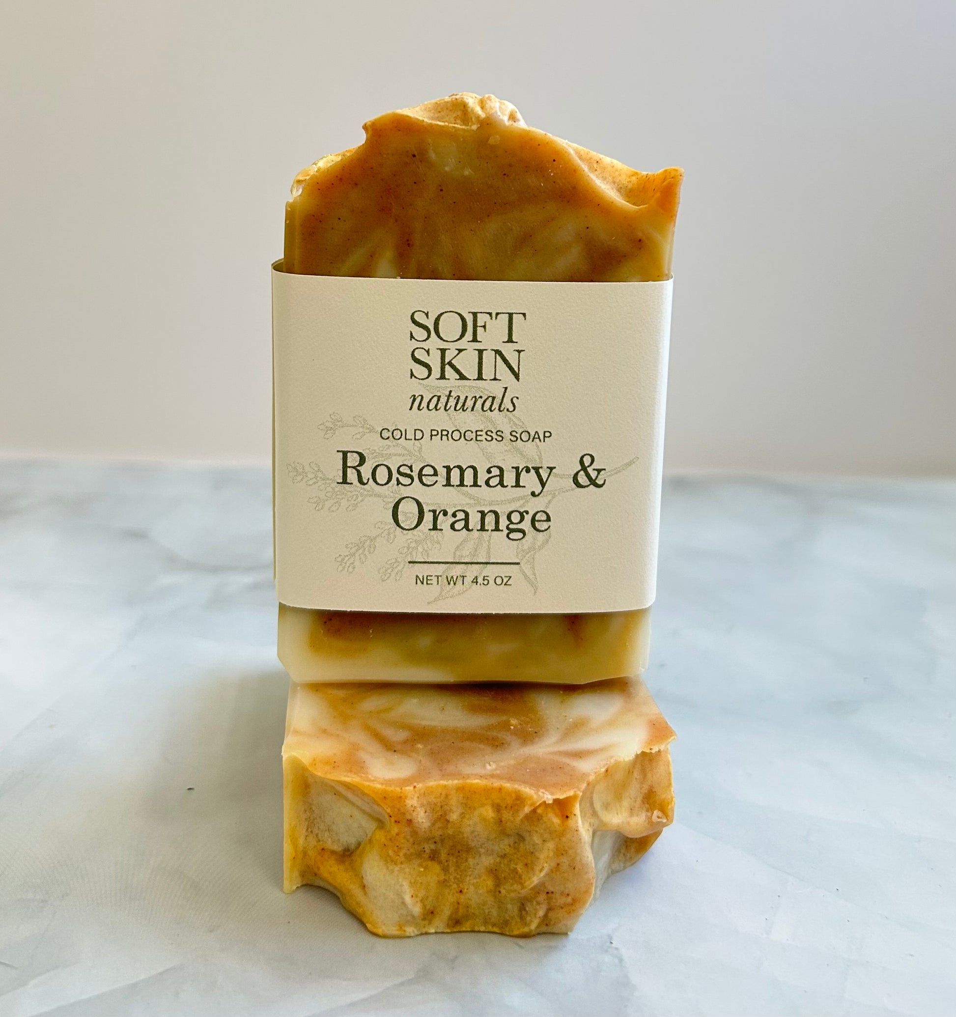 Two bars of soap with a 'Soft Skin Naturals' label on a marble surface