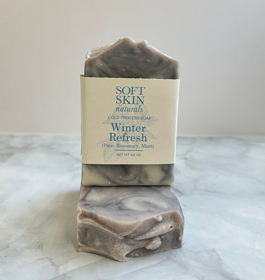Two bars of soap with a 'Soft Skin Naturals' label on a marble surface.