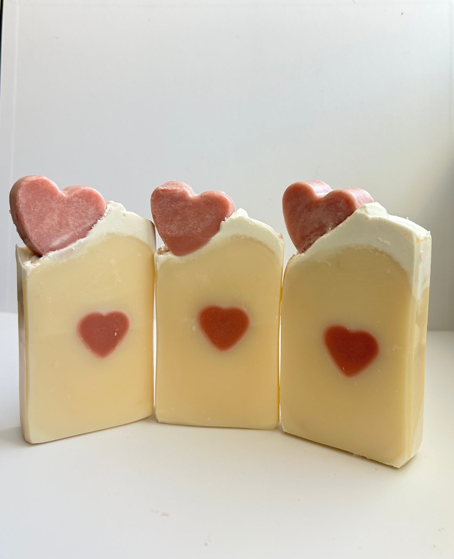 Three bars of soap with heart-shaped decorations on a white background