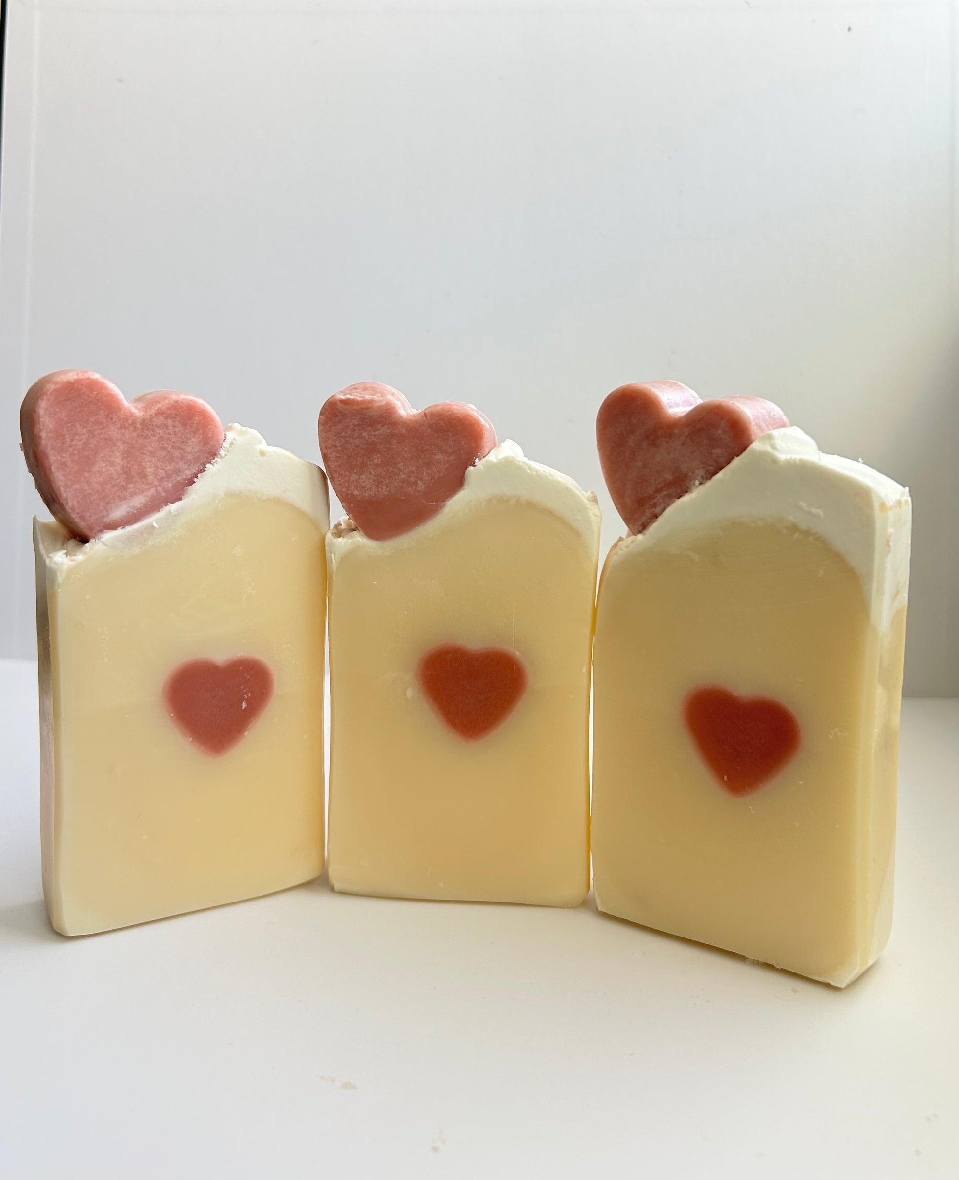 Three bars of soap with heart-shaped decorations on a white background